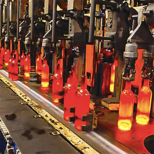 recently molded hot glass bottles being carried to next stage via robot hands